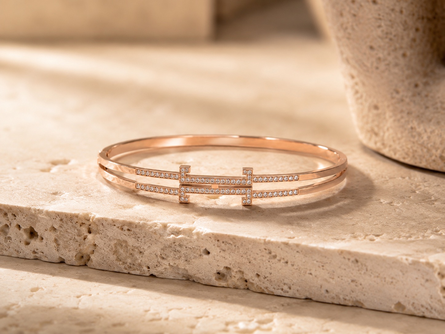 Le motif fondateur du Bracelet Éternel — les deux « T » se font face autour du point d'or : passé, présent, futur.
