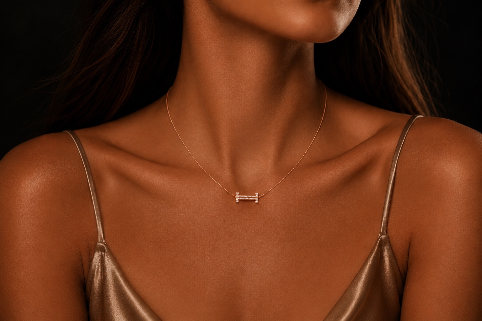 L'Éternel Intime — le pendentif aux deux « T » au creux du cou, porté à même la peau.